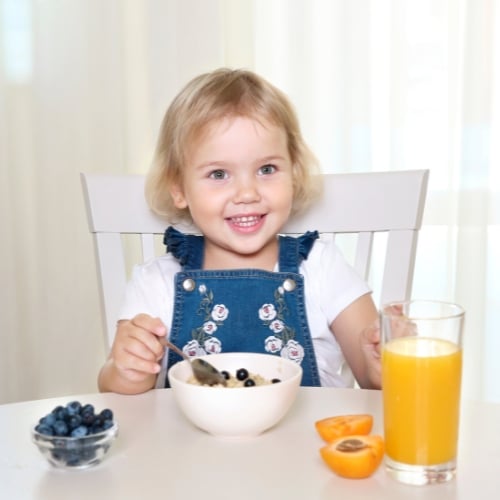 Child happily eating a bowl of oatmeal, a nutritious and soothing option for IBS.
